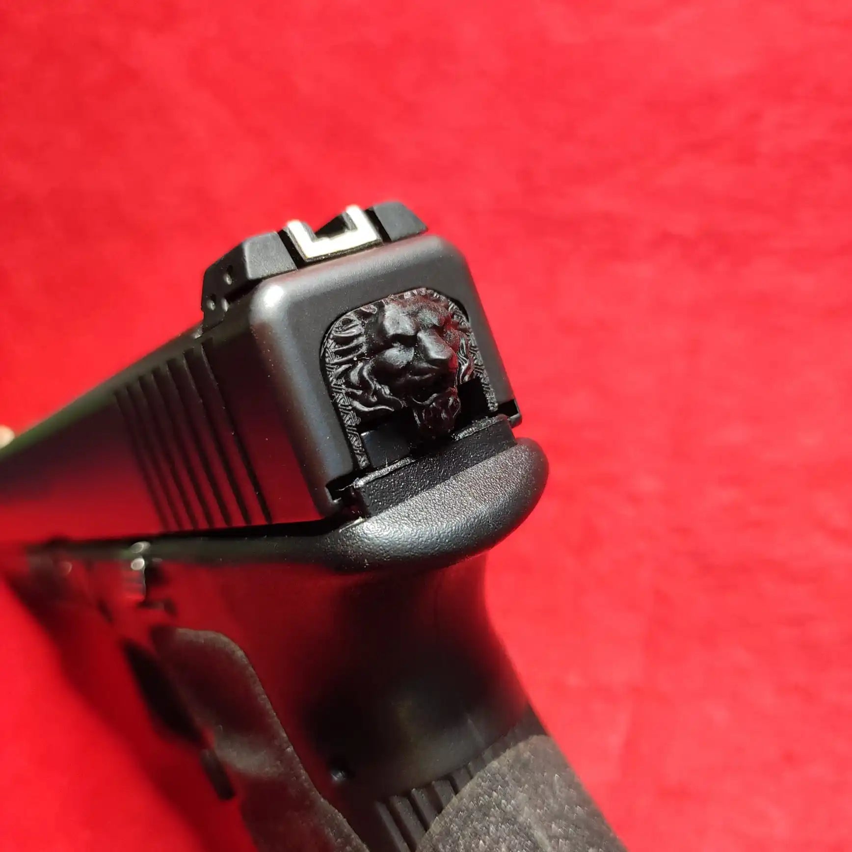 Black handgun with lion-head detail.