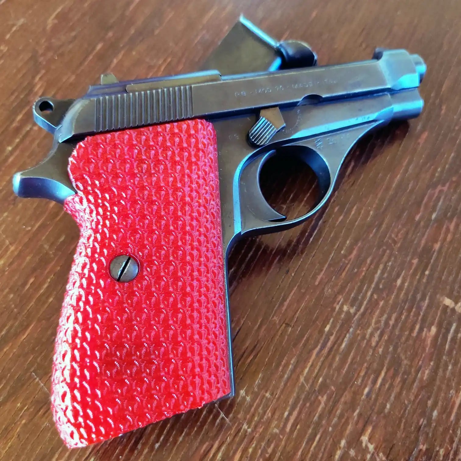 A black pistol with vibrant red textured grips.