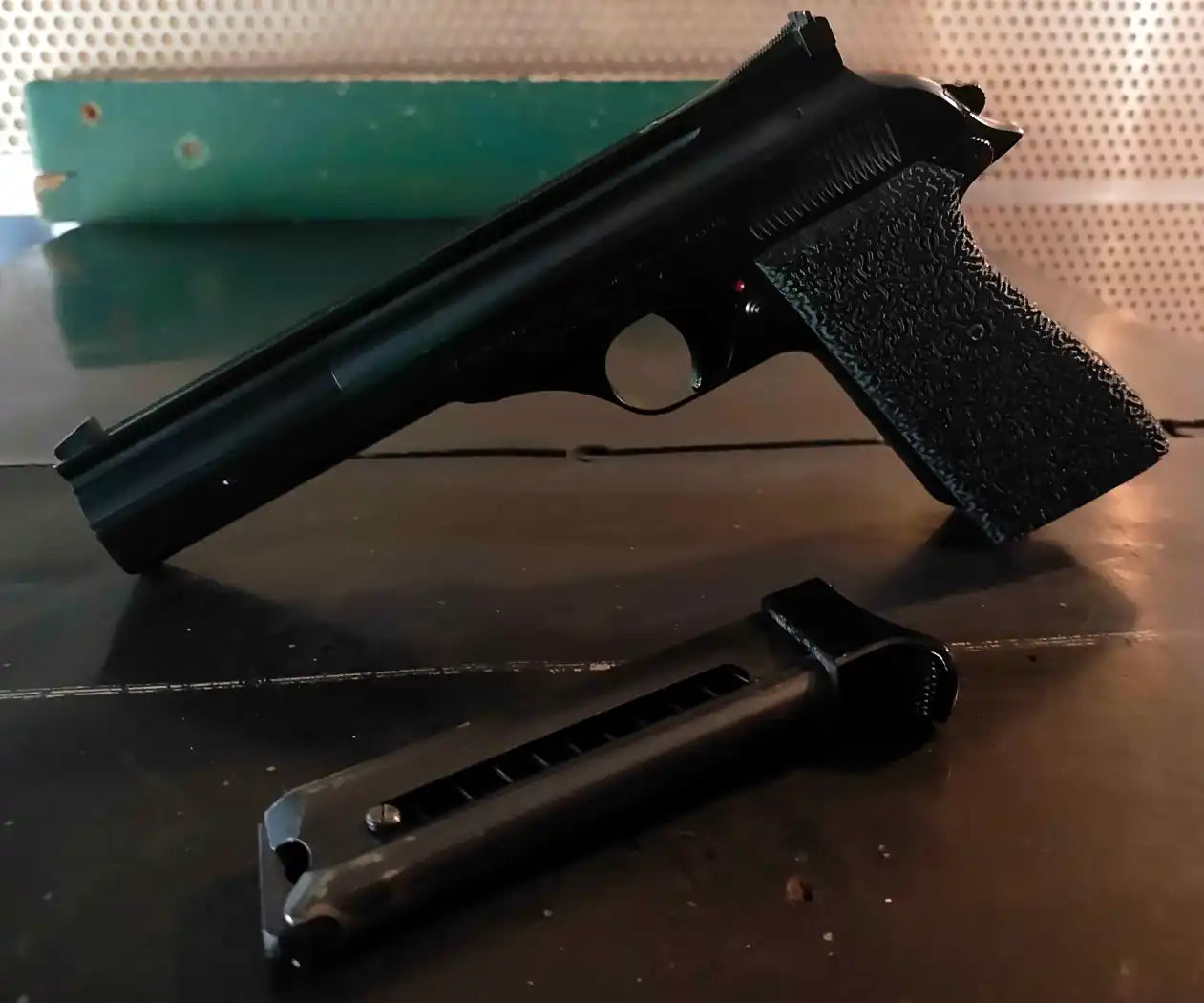 A black semi-automatic pistol with a textured grip and a detached magazine.